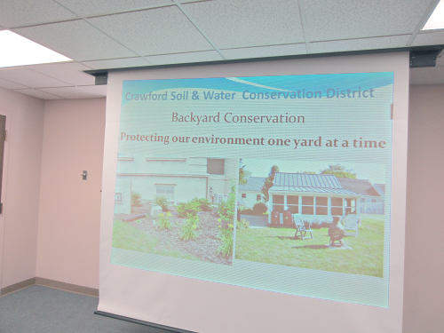 [photo - presentation projected onto a screen; slide reads Crawford Soil and Water Conservation District: Backyard Conservation Protecting our environment one yard at a time]