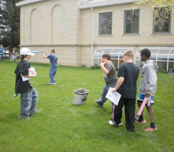 [photo of several boys playing in the yard near a wastebasket]
