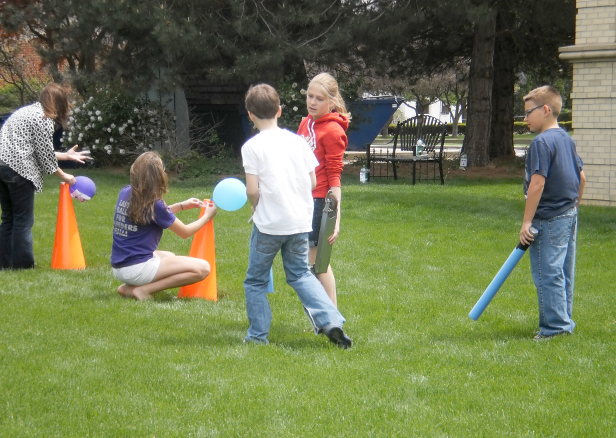 [photo of children playing in the yard with balls, traffic cones, and a foam noodle]