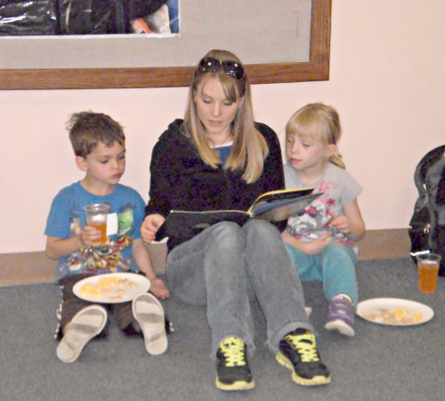 [photo of a woman reading to two young children]