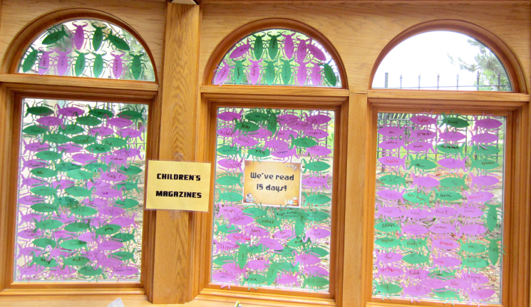 [photo: for each child who read 15 days, a beetle outline with the child's name was placed on the windows]