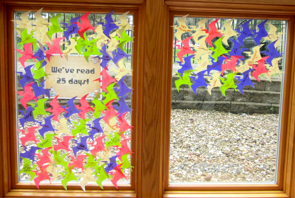 [photo: for each child who read 25 days, a pterosaur outline with the child's name was placed on the windows]